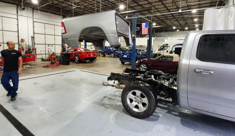 Auto body technicians working on truck frame and vehicle body repair inside Burnside Express Collision Greenwood Indiana repair facility.