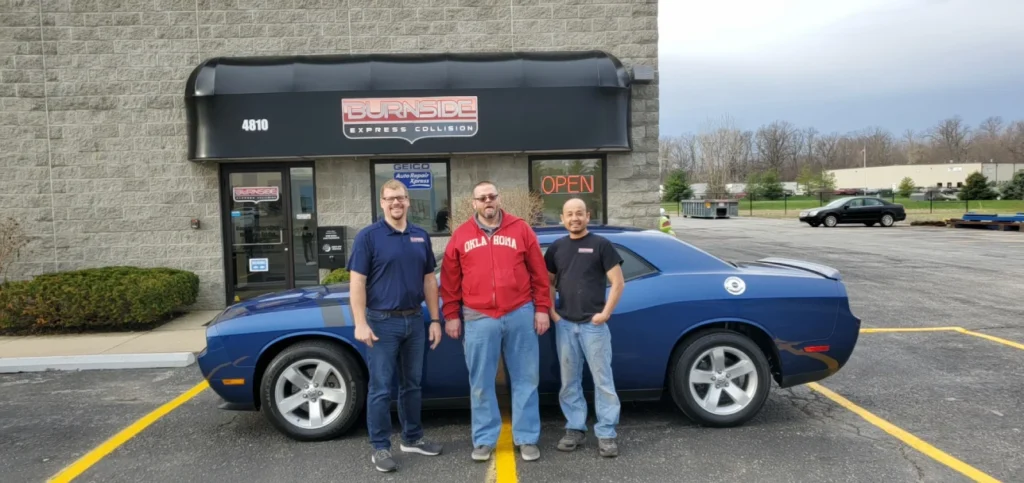 Burnside Express Collision team standing outside auto body shop in Greenwood Indiana with repaired vehicle.