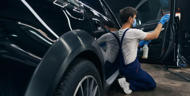 Auto body technician cleaning and detailing a repaired car at Burnside Express Collision Zionsville Indiana auto body shop.