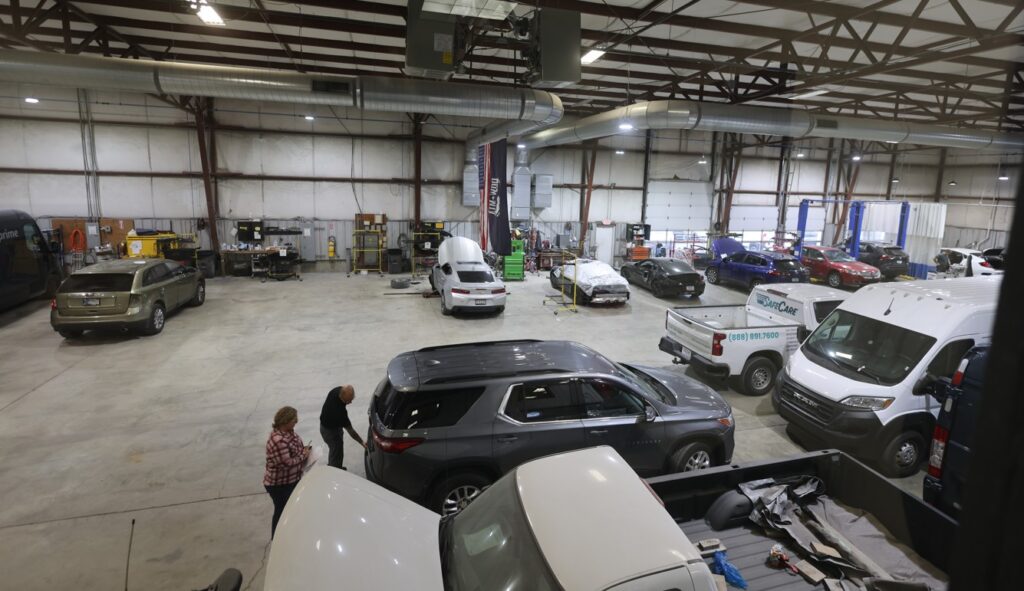 Wide interior view of Burnside Express Collision’s West Indianapolis auto body shop with multiple vehicles in repair bays.