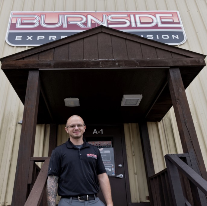 Manager standing in front of the Burnside Express Collision entrance at the West Indianapolis auto body repair shop.